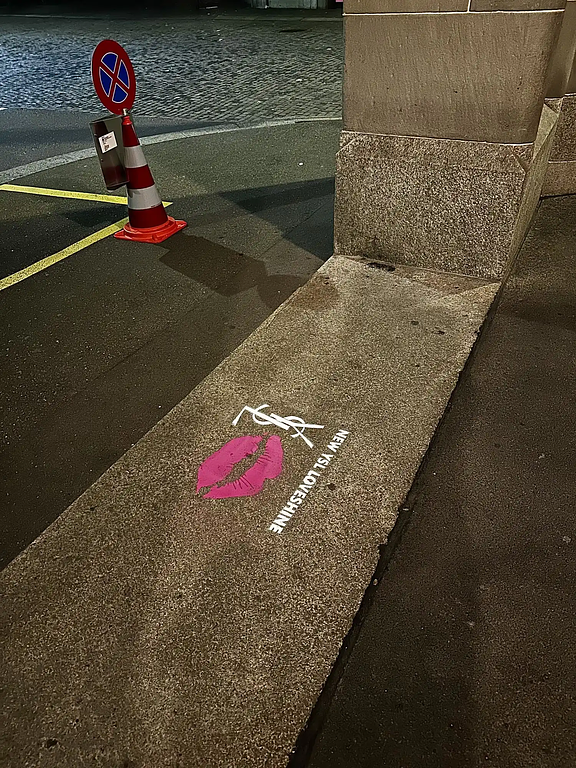 YSL Beauty chalk stencil featuring a pink lips graphic and logo on a city sidewalk at night