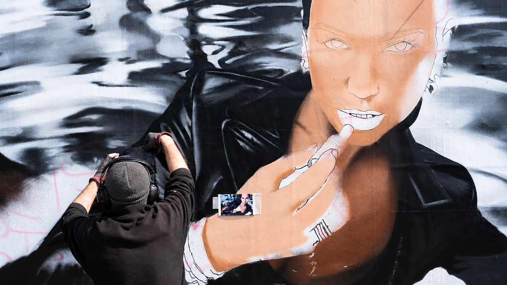 AKUT painting a hyperrealistic Yves Saint Laurent mural during the LOVESHINE campaign in Berlin